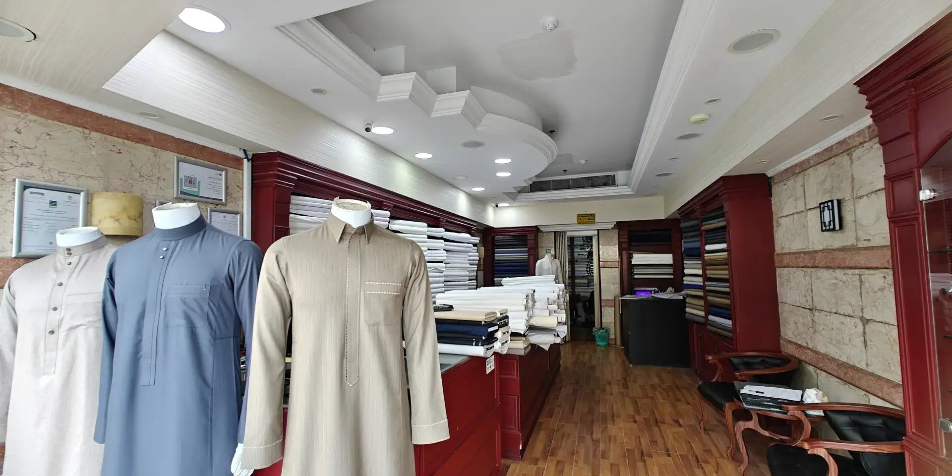 Inside the tailoring branch: mannequins in ready thobes and red wooden fabric shelves