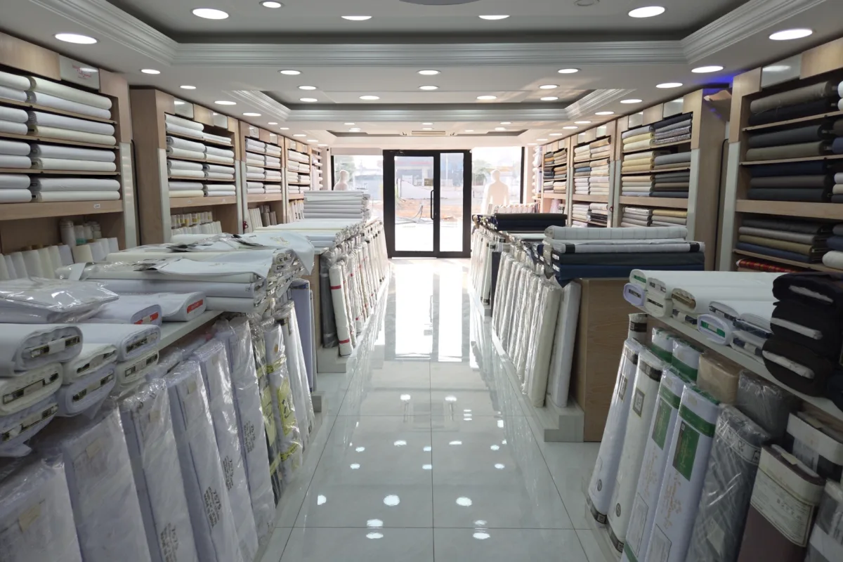 An aisle in a Ramada Al-Raqi branch between neatly arranged fabric shelves