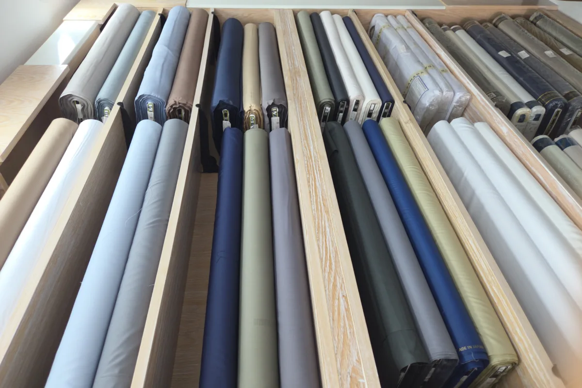 Fabric rolls in blue, grey, green and beige stacked on the shelves of a Ramada Al-Raqi branch