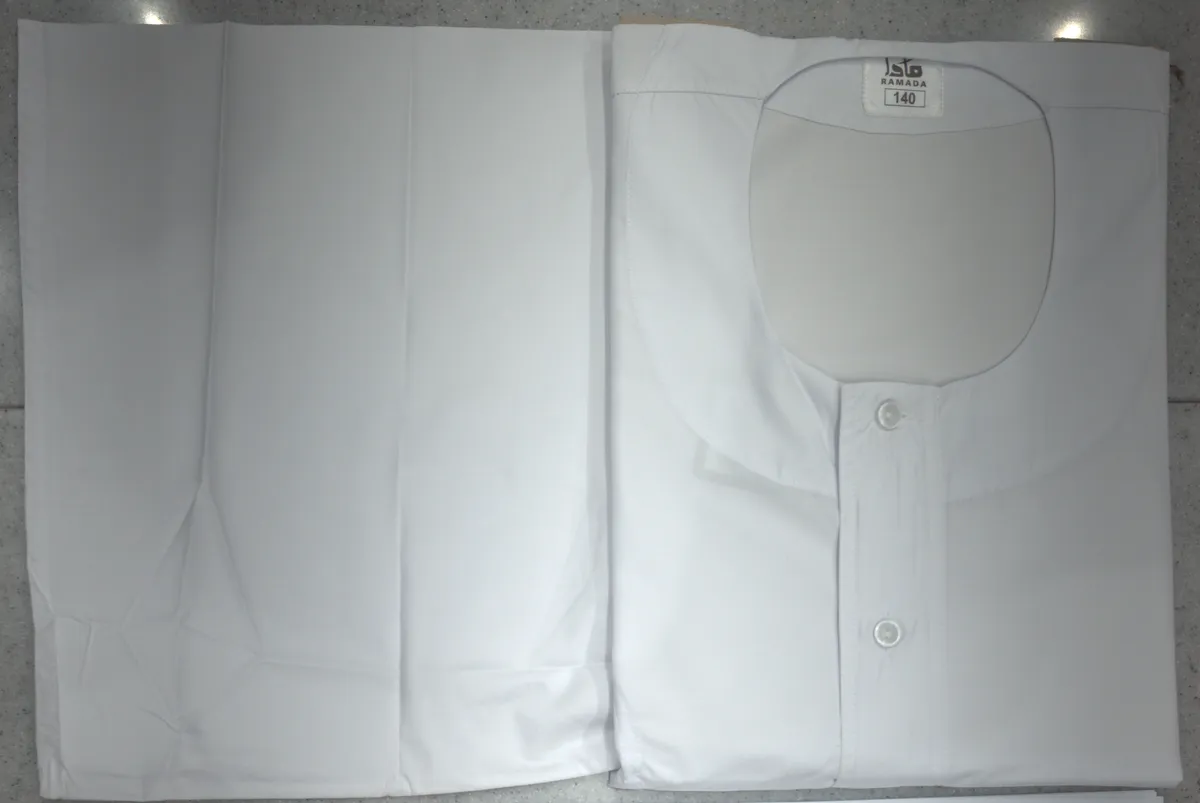 A folded white Sudanese jalabiya with a round collar and buttons