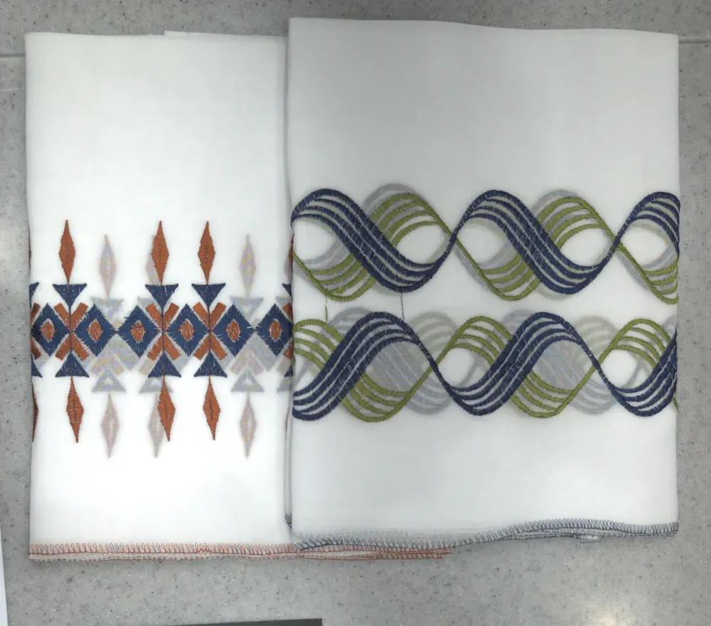Two white shawls with coloured embroidery in wavy and geometric patterns