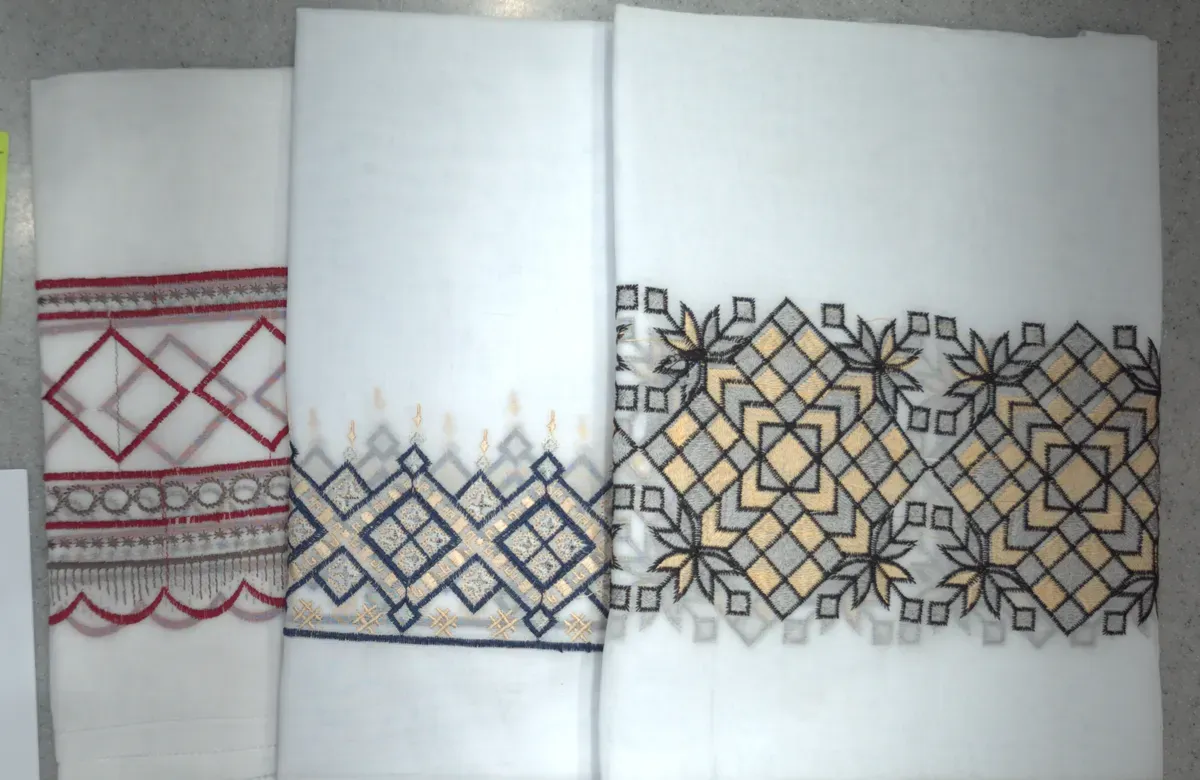 Folded white shawls with coloured geometric embroidery