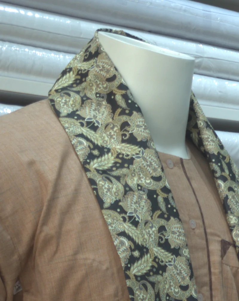 A mannequin in a brown jalabiya and a shawl printed with an ornamental pattern in olive and black