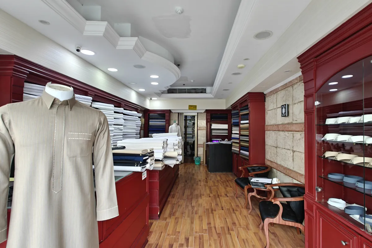 Inside Ramada Al-Raqi Tailoring: a thobe on a mannequin and shelves of thobe fabric